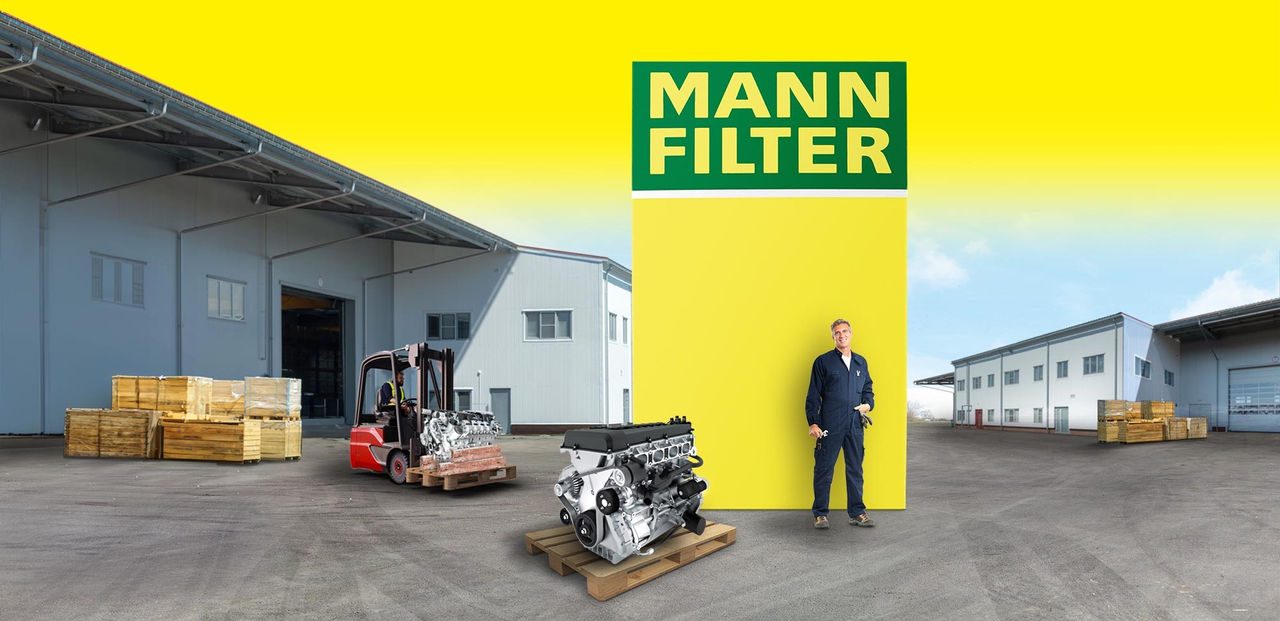 MANN-FILTER industrial & heavy engines Industrial engine and mechanic in front of a MANN-FILTER box, forklift and warehouse in background