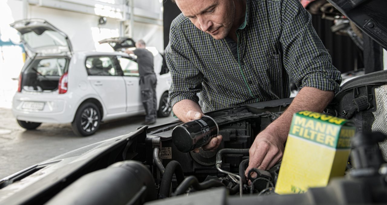 Workshop installing oil filter in car