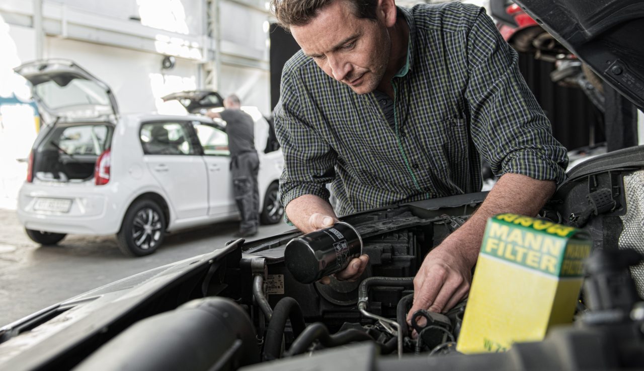 Workshop installing oil filter in car